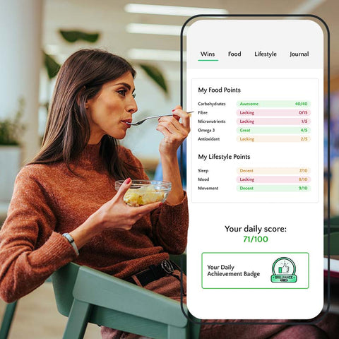 Woman eating a bowl of fruit with a smartphone displaying Clubwell app on a blurred background