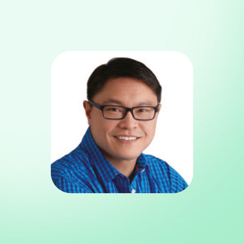 Dr Jason Fung wearing glasses and a blue shirt on a light green background
