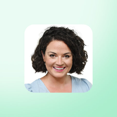 Emma Porter with short curly hair smiling on a light green background