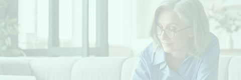 Person wearing glasses sitting on a couch with a blurred background