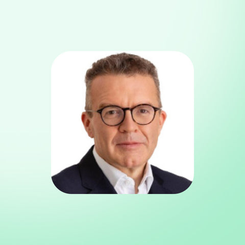 Tom Watson wearing glasses and a suit on a light green background