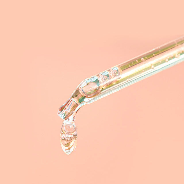 Clear glass straw with water droplets on a peach background