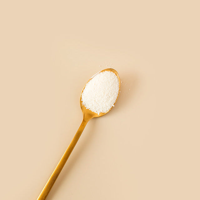 Gold spoon filled with white powder on a beige background
